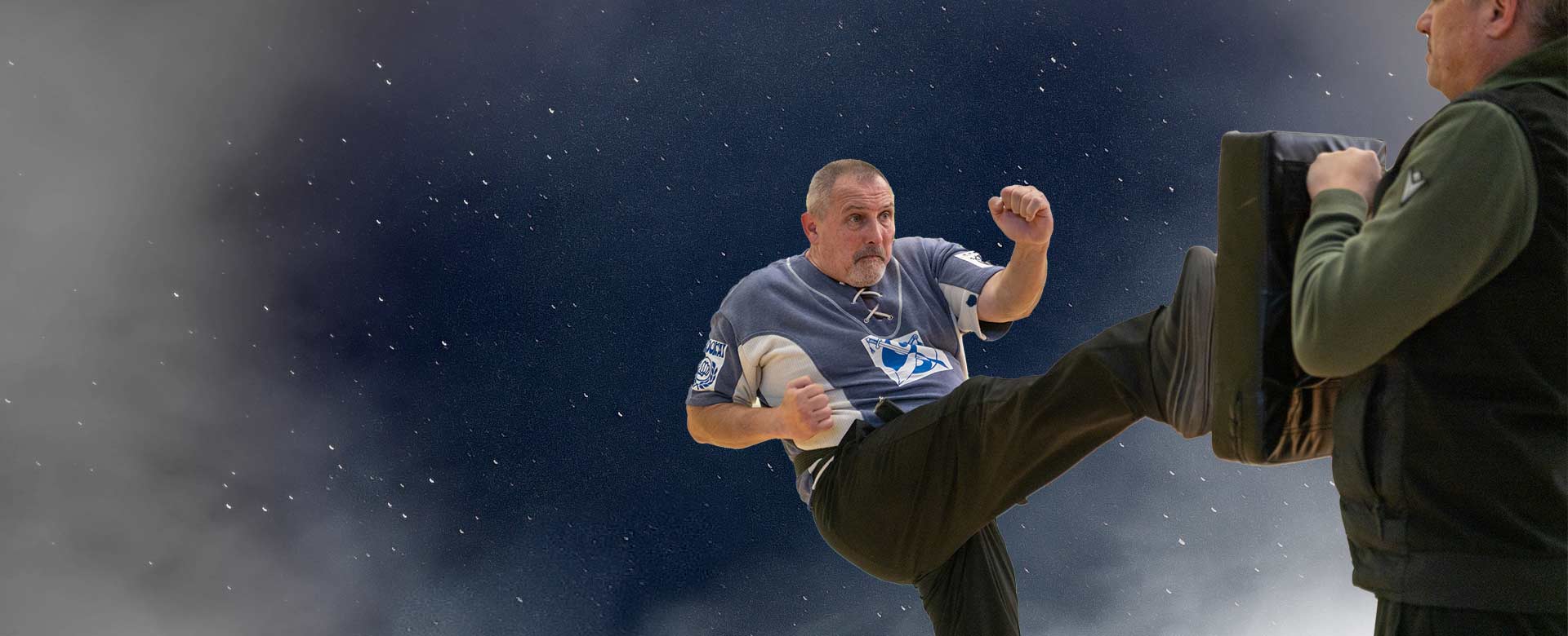 David Stainko izvodi visoki udarac nogom u fokuser koji drži partner